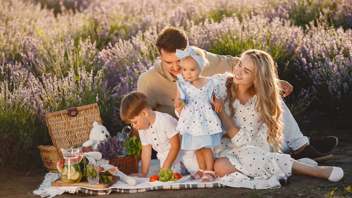 A joyful family with two children enjoying a summer picnic in a lavender field.